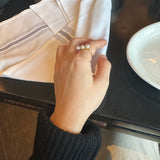 A gold ring with three freshwater pearls on a person's finger.