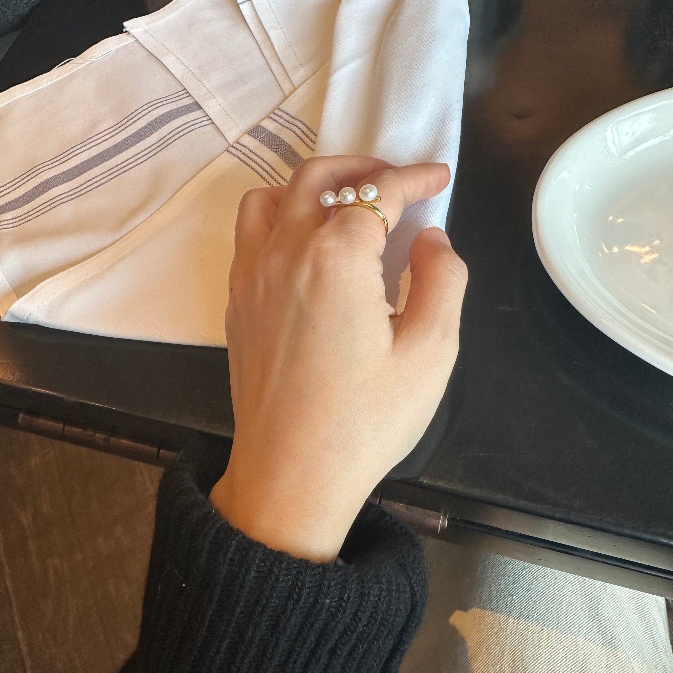 A gold ring with three freshwater pearls on a person's finger.