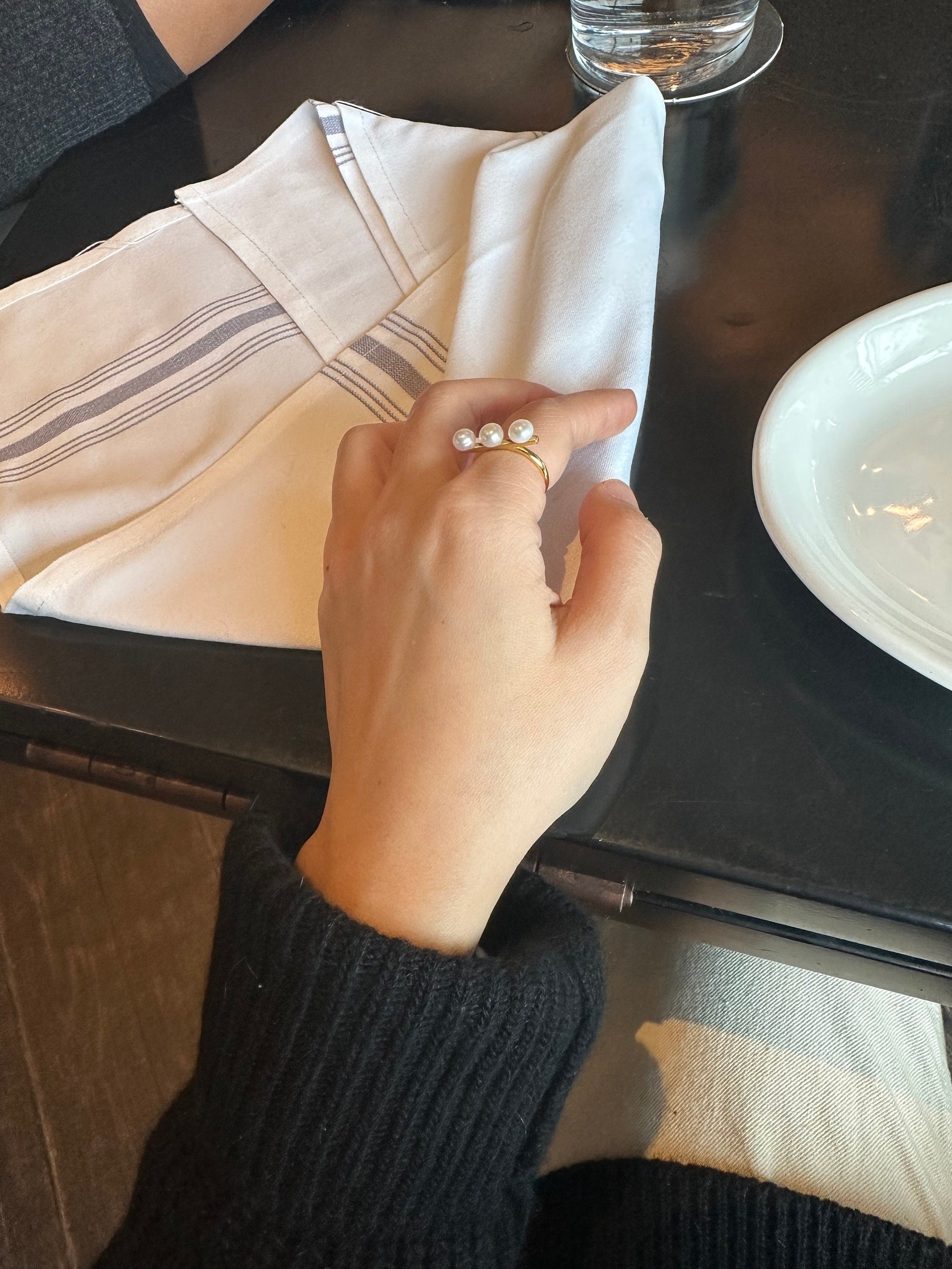 A gold ring with three freshwater pearls on a person's finger.