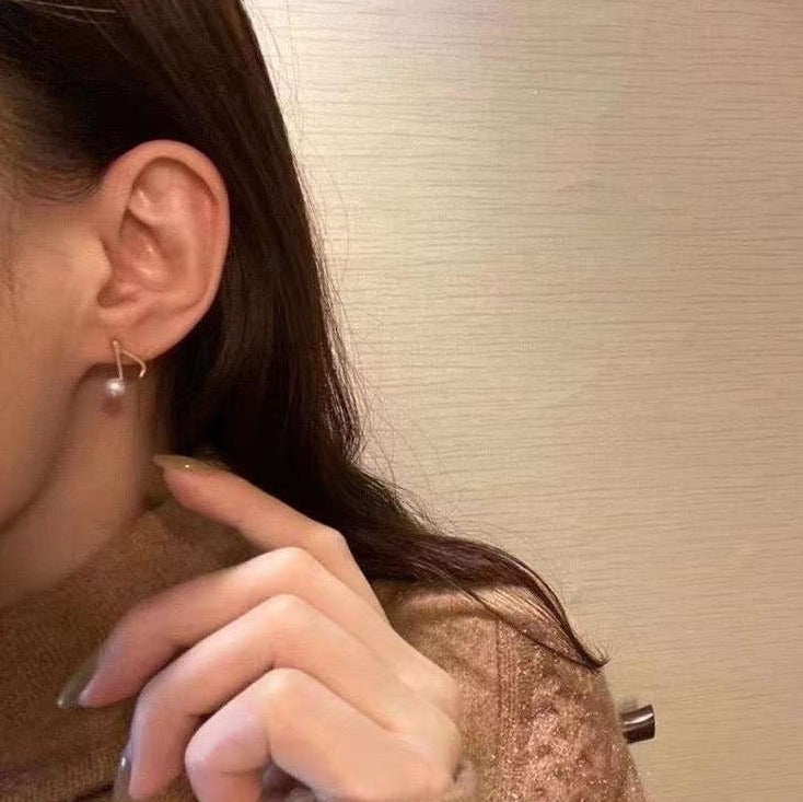 Fresh water pearl note stud earrings on a person's ear.