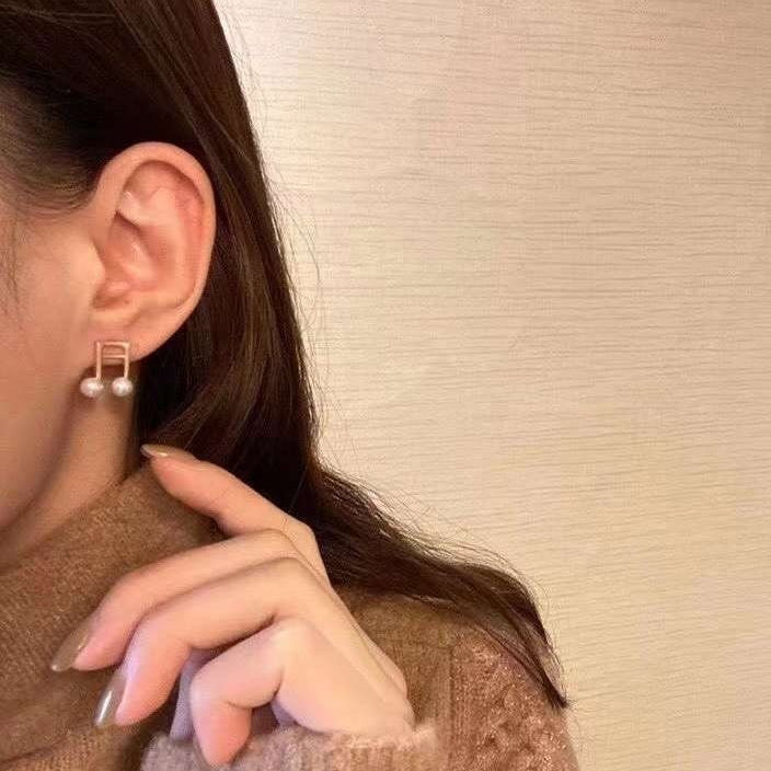 Freshwater pearl musical note stud earrings on a person's ear.